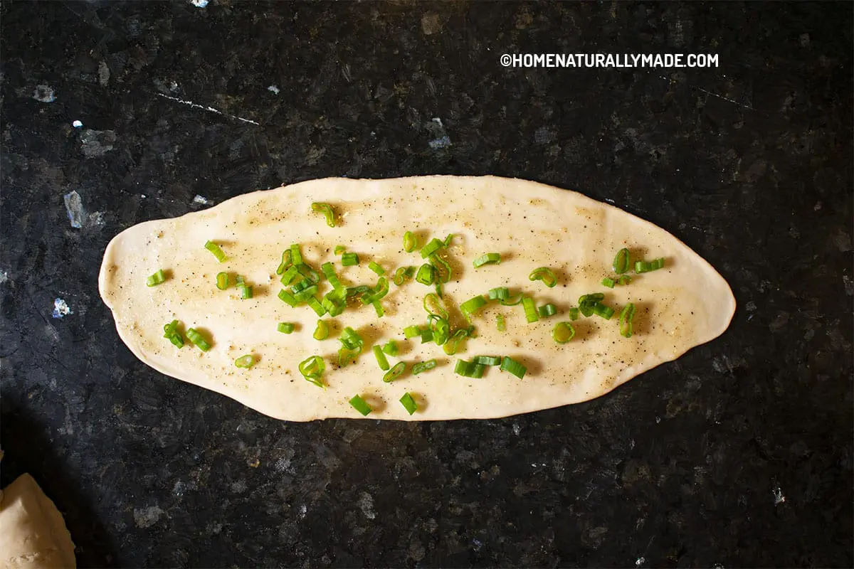 Brush the Filling over the flat dough sheet and sprinkle with green onions