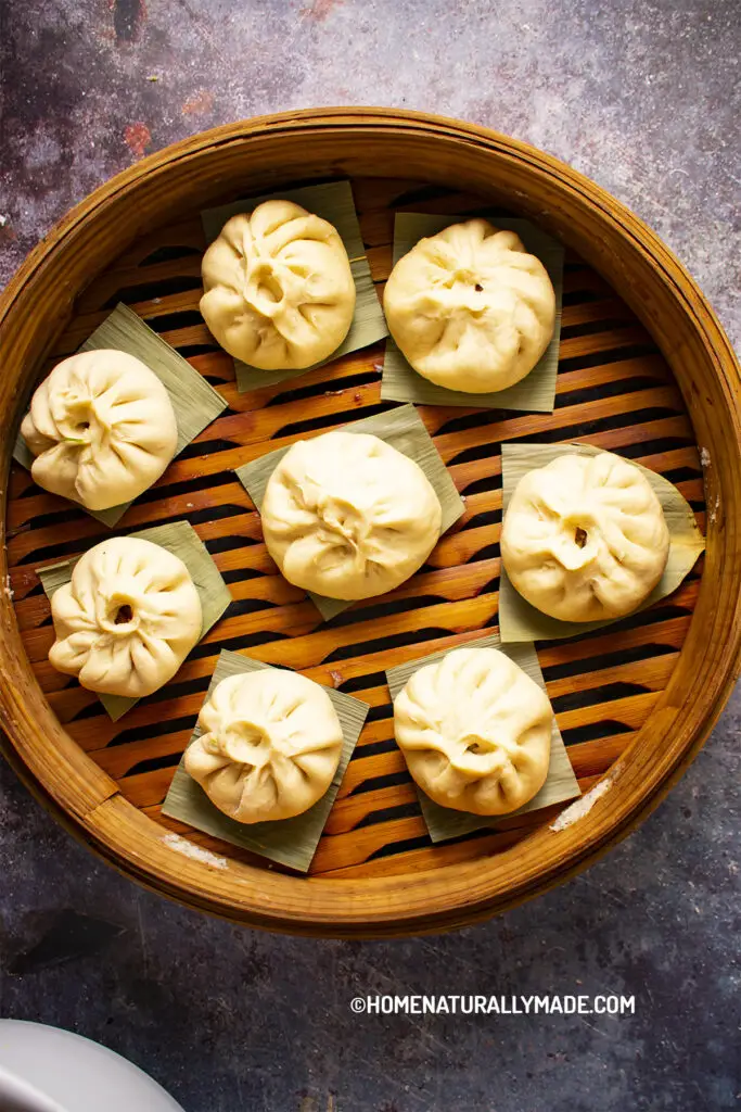 Freshly Wrapped Pork Buns in Steamer Sitting on dried bamboo leaves