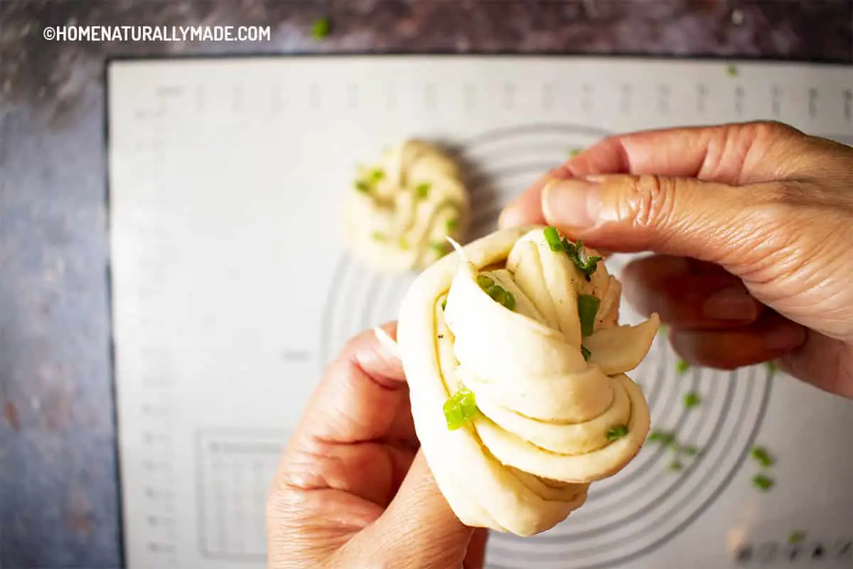 Wrap twisted dough strips into a bun for Chinese Flower Rolls