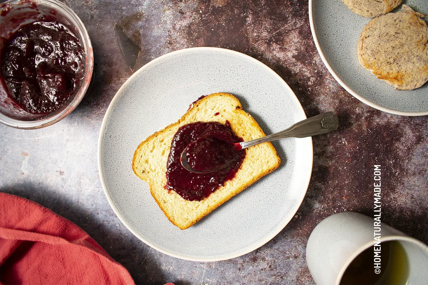 A slice of toast and bun with homemade cherry jam