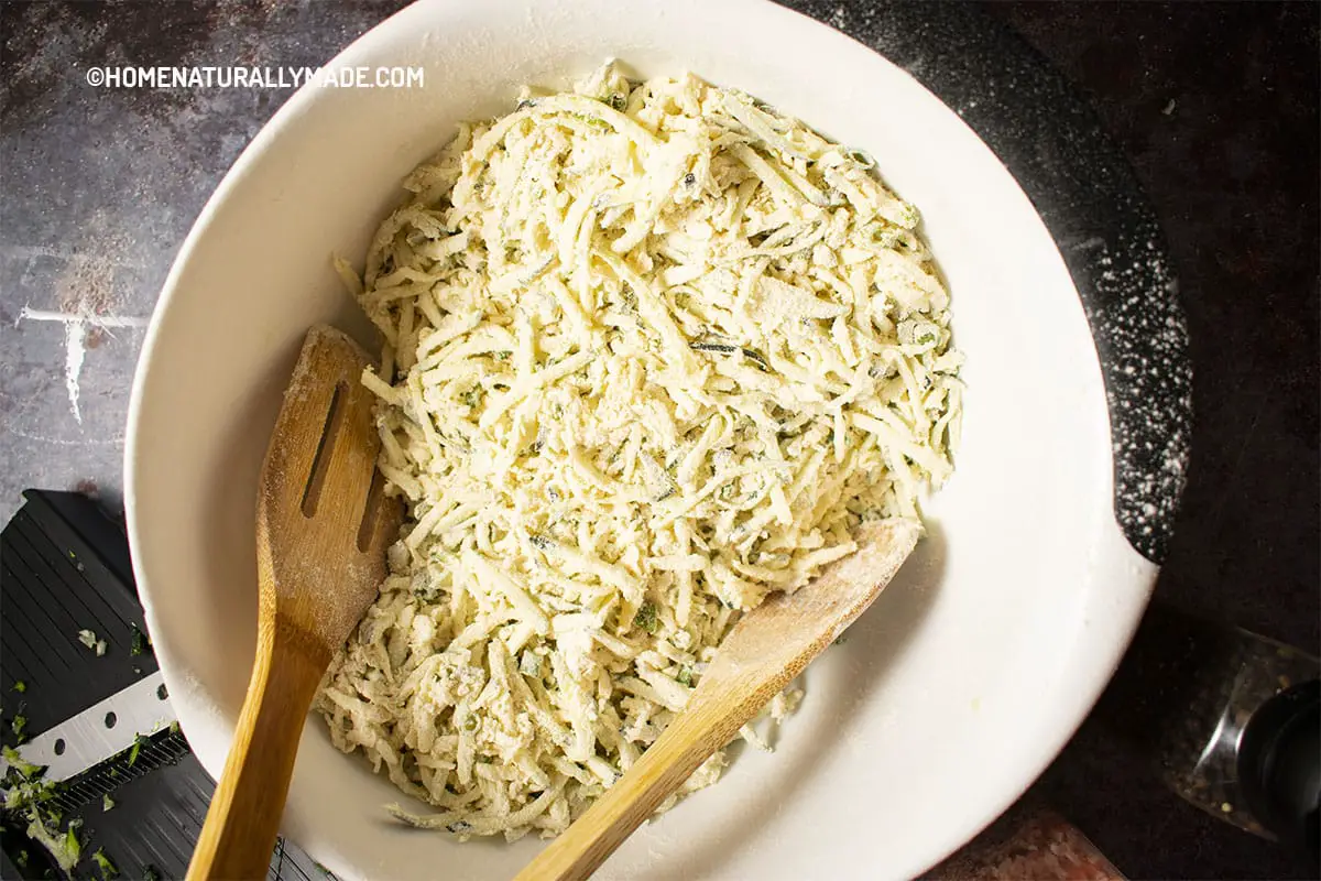 Mix Zucchini thin julienne cut slices with seasoning and flour for making Zucchini Fritters