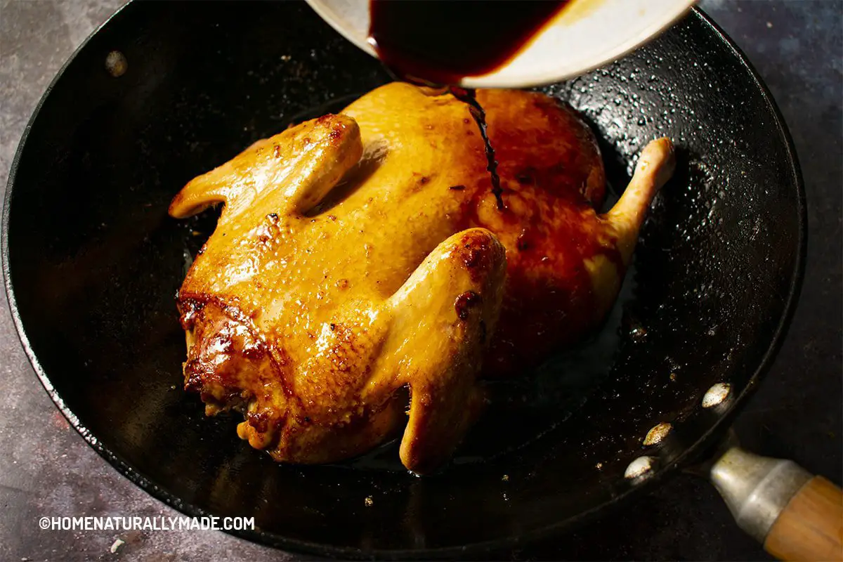 Pour braising juice over duck in the wok
