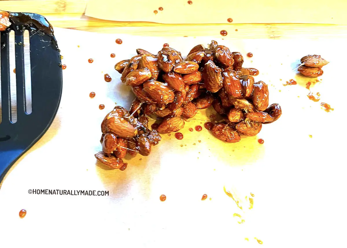 Almonds mixed with burnt sugar on the cutting board for making Candied Almonds