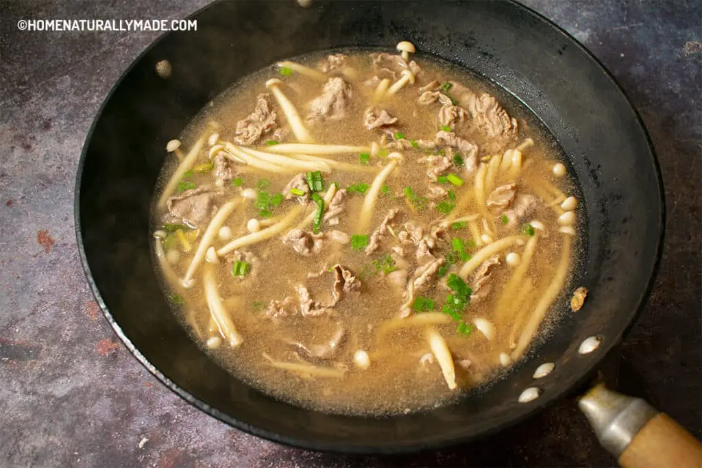Freshly cooked Fei Niu Fatty Beef soup with stringy mushrooms in the wok
