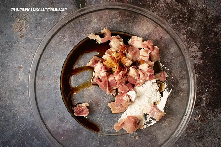 marinate pork cubes in a mixing bowl with Shaoxing wine, soy sauce, etc.