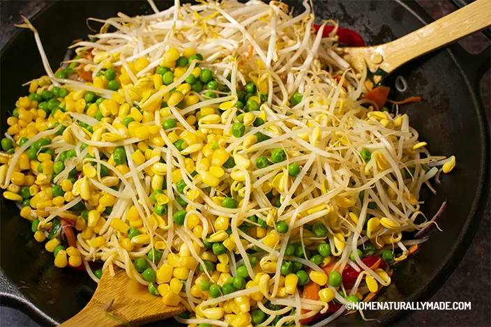 add mung beans, blanched soybean sprouts, corn and peas into the wok