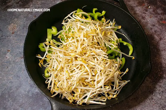 stir fry mung bean sprouts and green pepper slices in the cast iron pan