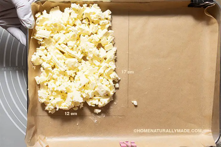 cut butter into tiny cubes and form an even layer in the stainless baking pan lined with parchment paper