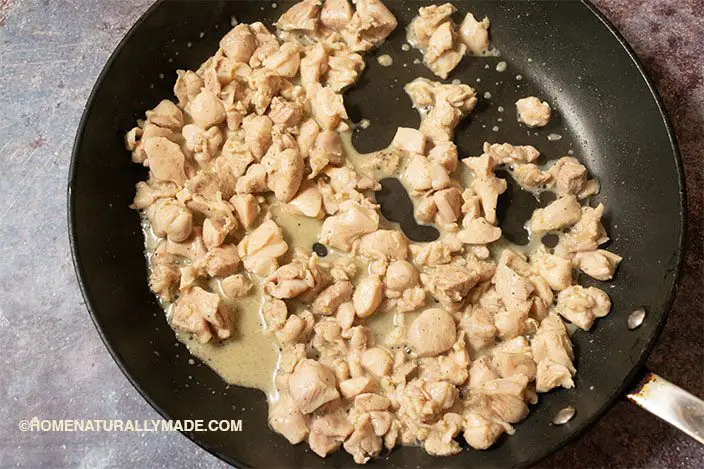 cooking marinated chicken thigh meat chunks in a frying pan